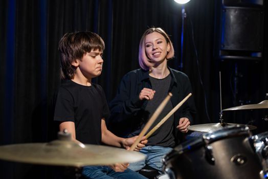 Young woman teaching boy to play drums