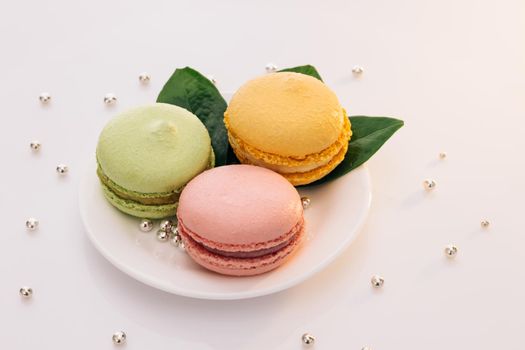 Multicolor macarons , french macaroon, greedy pastry. French dessert sweets colored macaroons cookies arranged on a while plate on white background.