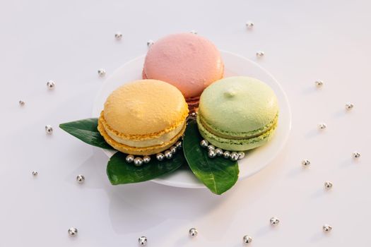 Colorful macarons in white plate. Macarons dessert. Many cute colors Assortment of pastel colored macaron of different flavors.