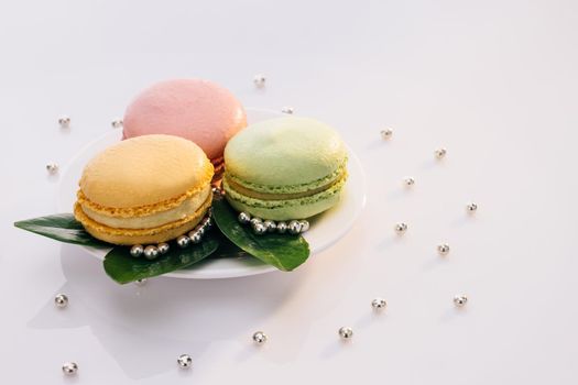 Macarons on white reflective glass, sweet tasty desserts. Multicolor macarons , french macaroon, greedy pastry. French dessert sweets colored macaroons cookies arranged on a while plate.