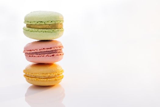 Three macarons against a bright white background. Sweet colorful macarons isolated on white background. Tasty colourful macaroons.