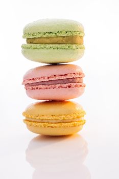 Vertical stack of three macarons against a bright white background. Sweet colorful macarons isolated on white background. Tasty colourful macaroons.