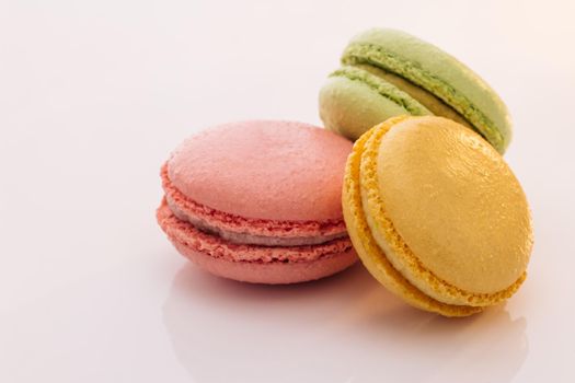 Three cookies macaroons are stacked on top of each other. Traditional French multicolored macaroon. Macaroons on white background. Food concept