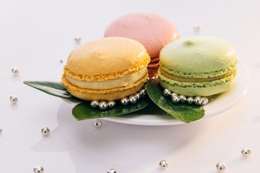 Close up of multicolor macarons , french macaroon, greedy pastry. French dessert sweets colored macaroons cookies arranged on a while plate on white background.