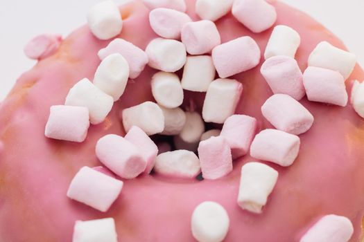 Colorful frosted pink doughnut. Close-up shot of pink tasty delicious sweet donut with colorful sprinkles on purple background. Dessert.