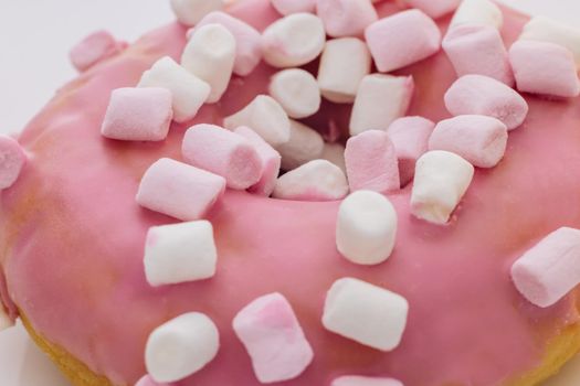 Close-up shot of pink tasty delicious sweet donut with colorful sprinkles on purple background. Dessert. Colorful frosted pink doughnut