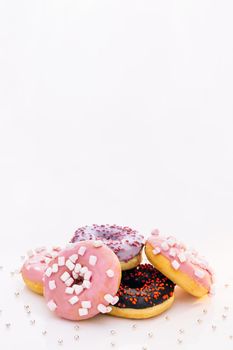 Donuts with different fillings on the white table. Assortment of donuts of different flavors. Chocolate frosted, pink glazed and sprinkles donuts.