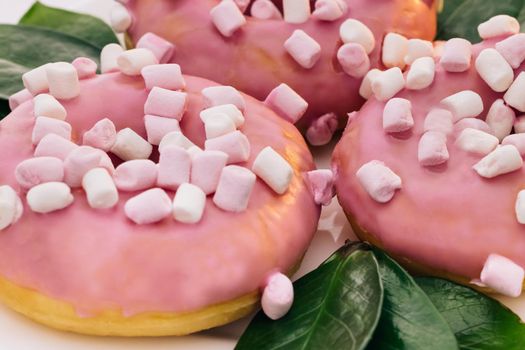Close-up of a delicious round donuts covered with sweet icing rotates on a bright background. Sweet dessert pink donuts.