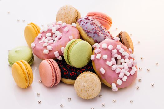 Many multi-colored macarons donuts with different tastes, dessert. French macaroons. Macaroons and donuts on a white background.