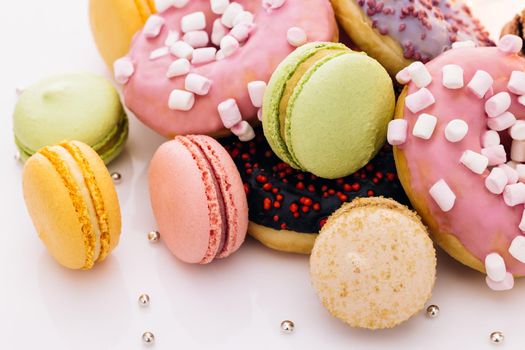 Macaroons and donuts on a white background. Many multi-colored macarons donuts with different tastes, dessert. French macaroons.