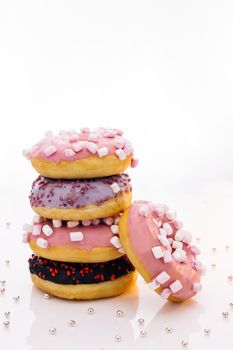 Tasty delicious sweet do nut with colorful sprinkles on white background. Shot of five sweet doughnuts stacked on top of each other in the form of a tower.