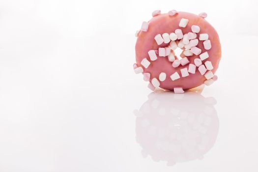 Tasty rotating donut on white background. Close-up shot of pink tasty delicious sweet donut with colorful sprinkles on white background. Dessert. Colorful frosted pink doughnut.