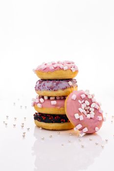 Tasty delicious sweet do nut with colorful sprinkles on white background. Shot of five sweet doughnuts stacked on top of each other in the form of a tower.