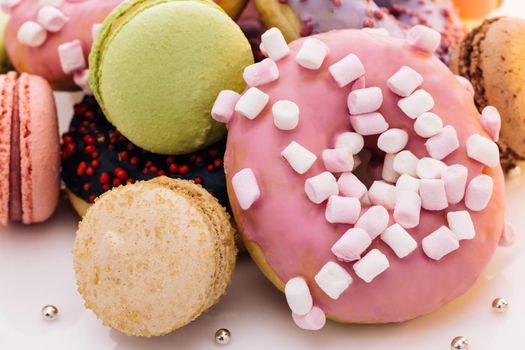 Many multi-colored macarons donuts with different tastes, dessert. French macaroon. Macaroons and donuts on a white background.