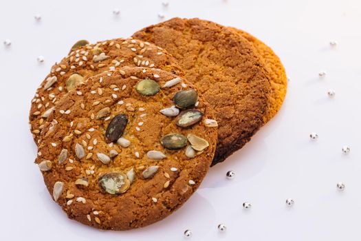 Wheat fall on dietary cookies. Eat oatmeal cookies. Oatmeal cookie on the table with sesame seeds on white background. The concept of making chip cookies.