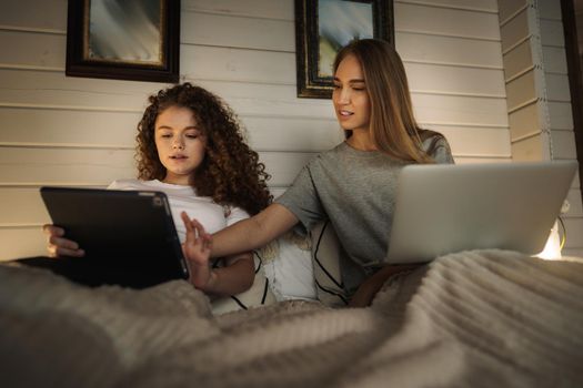 Two beautiful women lying in bed, holding and watching laptop