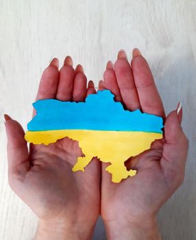 Map of Ukraine in the color of the Ukrainian flag on the palms of a girl.