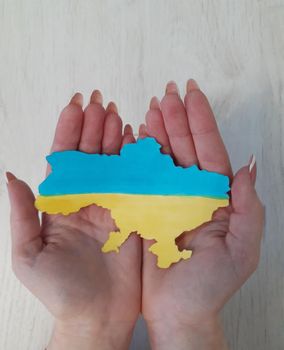 Map of Ukraine in the color of the Ukrainian flag on the palms of a girl.