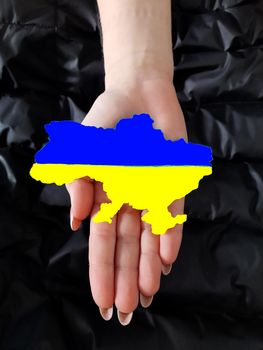 Map of Ukraine in the colors of the Ukrainian flag in the palm of a girl.