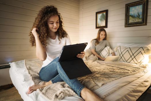 Two beautiful women lying in bed, holding and watching laptop