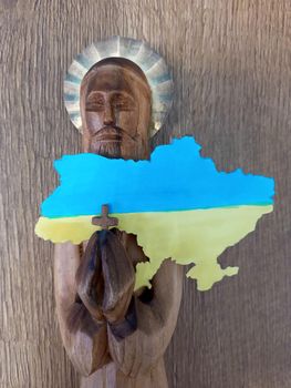 Wooden figurine of a saint with a map of Ukraine in the color of the yellow-blue Ukrainian flag.
