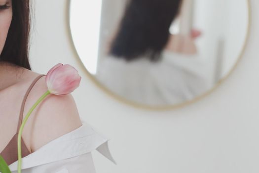 spring portrait of a young woman with pink fresh tulip on white background.