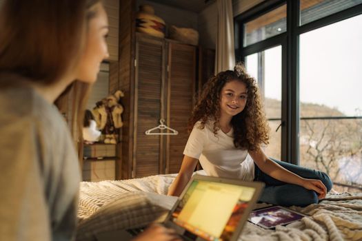 Two beautiful women lying in bed, holding and watching laptop