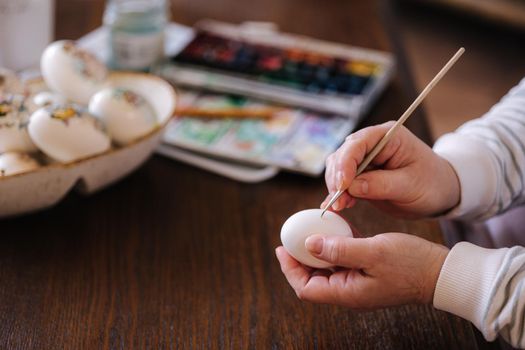 Woman painting a water colors on fantasy chicken eggs for Easter egg festival. Female drawing little yellow chick. The symbolic of Easter egg festival concept.