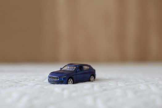 Miniature blue plastic toy car on textile material macro shot. close-up.