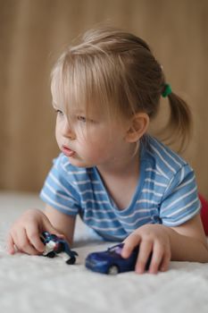 Portrait of child playing with toy cars indoors. Toddler having fun.