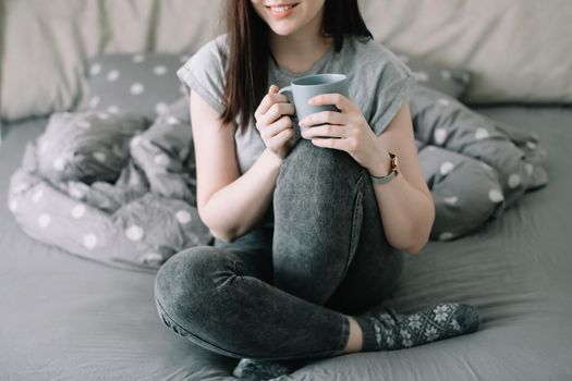 morning, coziness, cozy home concept - a young woman with cup of coffee or cacao in bed at home.