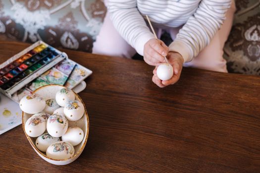 Top view of woman painting a water colors on fantasy chicken eggs for Easter egg festival. Female drawing little yellow chick. The symbolic of spring. Easter concept.