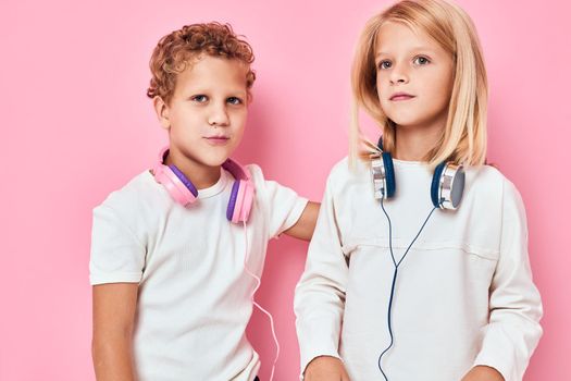 Active young people stand next to in headphones pink color background. High quality photo