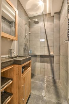 The interior of the bathroom in gray tones with a marble sink and a glass shower cabin