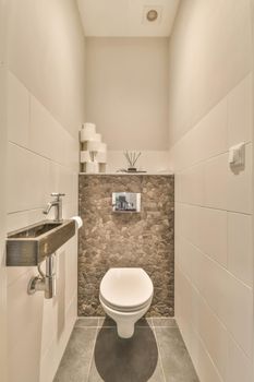 Toilet in a modern house with a stone back wall and a marble sink