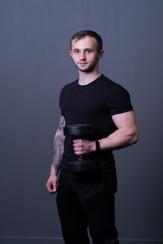 A guy with dumbbells in a black T-shirt muscular man sport posing, from aged dumbbells for male from body athletic, adult muscle. Active bodybuilder exercise, gym young