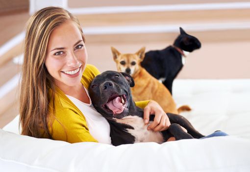 Portrait of an attractive young woman sitting with her pets on the sofa.