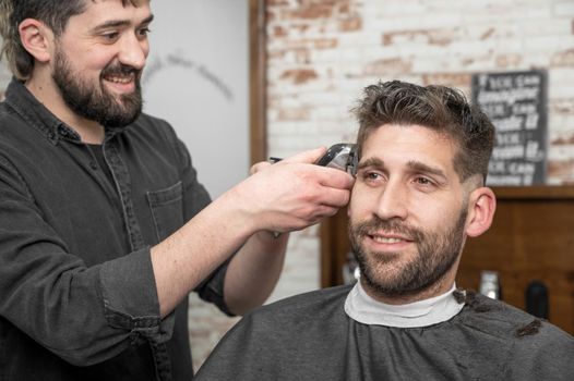 Closeup of happy man getting an haircut, in hair salon. High quality photo.