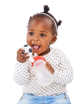 Studio shot of a baby girl holding a bottle and a toy.