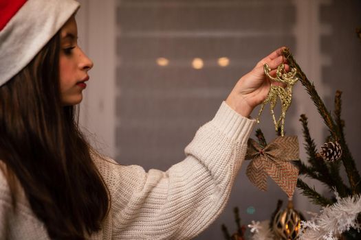 A young woman decorates a Christmas tree according to Polish tradition. An important annual Christmas ritual among Christians.