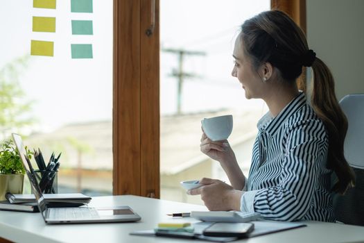 Asian Business Woman or Accountant with coffee at office.