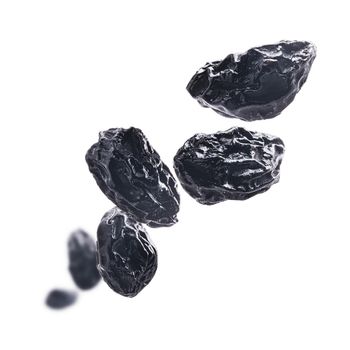 Dried prunes levitate on a white background.
