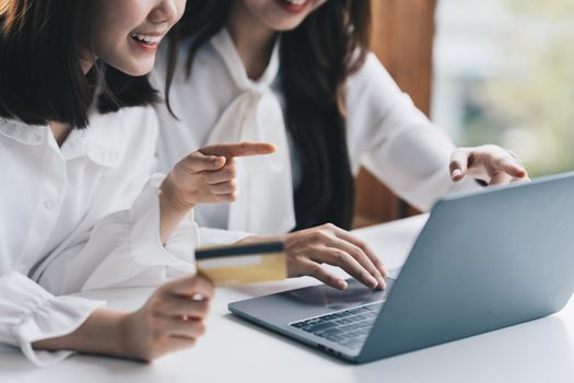 Two woman choosing travel trip package and using online payment by credit card