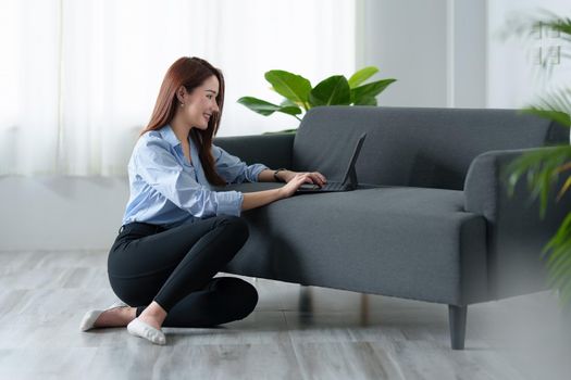 Woman enjoy with content streaming movies or social media application on digital tablet sitting near sofa at home