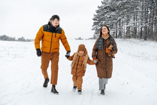 Happy family having a walk in winter outdoors in snow forest together