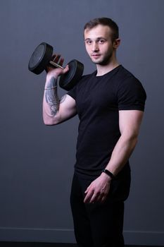 A guy with dumbbells in a black T-shirt muscular man sport holding, In the afternoon aged headphones in shirt from athlete athletic, adult muscle. Active biceps lifting, bodybuilding young