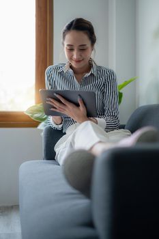 Woman enjoy with content social media application on digital tablet lay down on sofa at home.