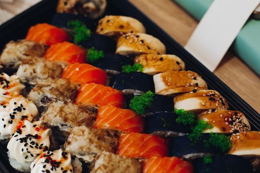 Colorful delicious mouthwatering sushi set laying on the plate including different ingredients: fish, caviar, rice, cucumber, salmon, soy sauce, wasabi, sesame seeds. An interesting presentation.