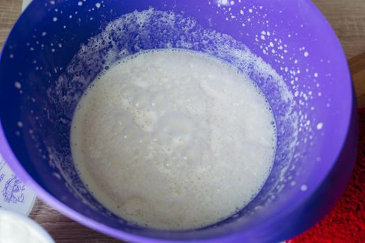 View of home made dough in big rounded plate for red cakes on table, preparing for cooking. Sweet bake on wooden table. Concept of bake and sweet food.