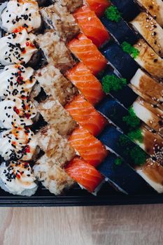 Colorful delicious mouthwatering sushi set laying on the plate including different ingredients: fish, caviar, rice, cucumber, salmon, soy sauce, wasabi, sesame seeds. An interesting presentation.